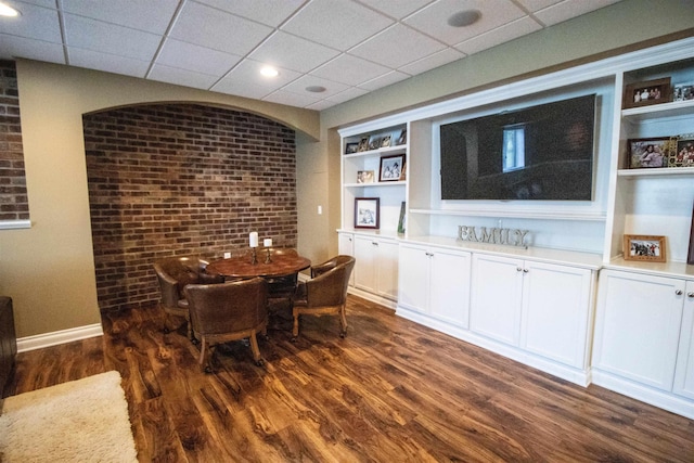 7380 Vassar Rd, Grand Blanc, MI 48439 - dining room with dark wood finished floors, a paneled ceiling, brick wall, and built in features