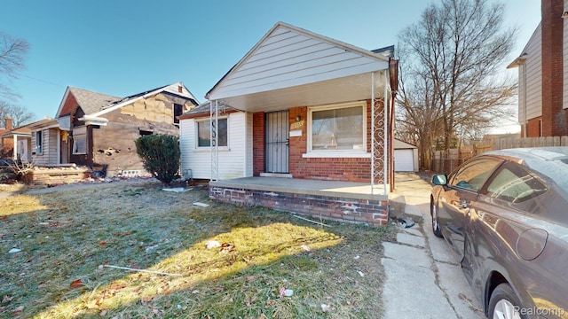 12660 Duchess St, Detroit, MI 48224 - view of front facade featuring a porch, brick siding, an outdoor structure, and a detached garage