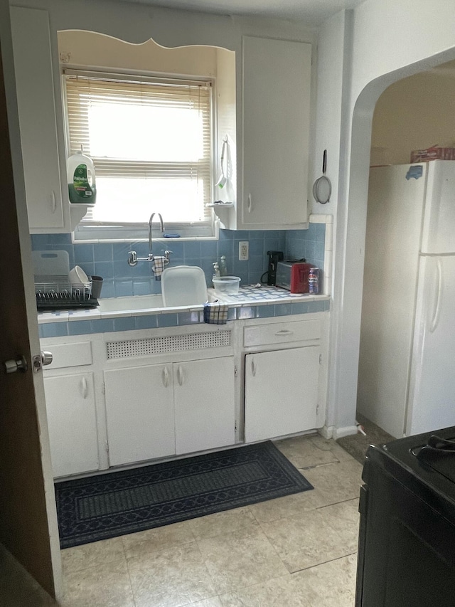 19624 Anglin St, Detroit, MI 48234 - kitchen with freestanding refrigerator, tile counters, backsplash, and white cabinetry