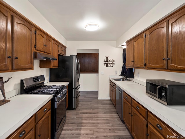 32721 Stoneybrook Ln, Macomb, MI 48026 - kitchen featuring appliances with stainless steel finishes, under cabinet range hood, light countertops, dark wood-style floors, and brown cabinetry