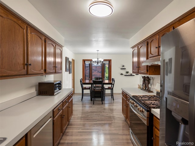32721 Stoneybrook Ln, Macomb, MI 48026 - kitchen featuring stainless steel appliances, under cabinet range hood, a chandelier, light countertops, and light wood-type flooring