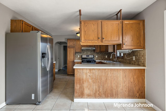 602 Elsa St, North Muskegon, MI 49445 - kitchen featuring stainless steel appliances, under cabinet range hood, a peninsula, tasteful backsplash, and light tile patterned floors