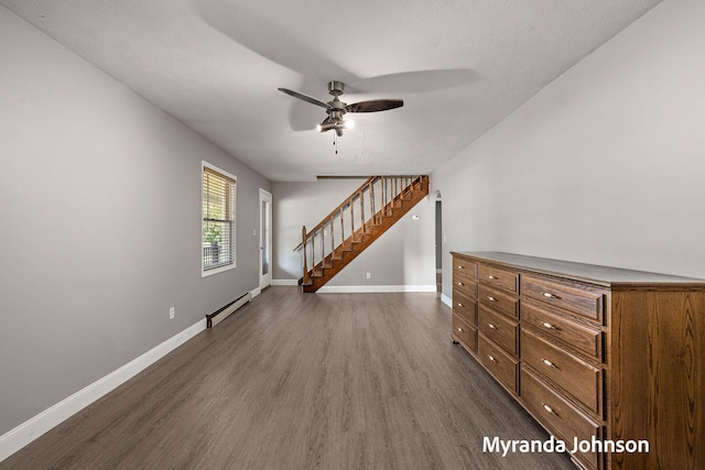 602 Elsa St, North Muskegon, MI 49445 - spare room featuring dark wood-style floors, a baseboard heating unit, a ceiling fan, and stairs