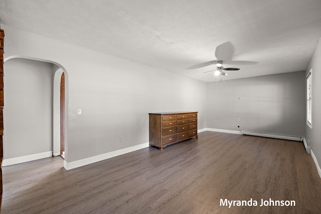 602 Elsa St, North Muskegon, MI 49445 - spare room featuring a baseboard radiator, arched walkways, a ceiling fan, and dark wood-style flooring