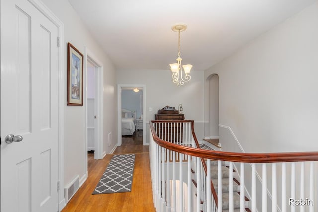 119 Bristol Ave NW, Grand Rapids, MI 49504 - hallway featuring an upstairs landing, light wood-type flooring, a chandelier, and arched walkways