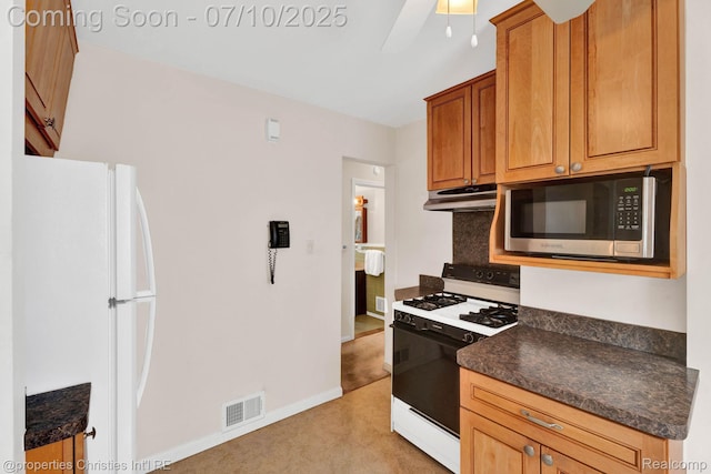 816 E 3rd St, Royal Oak, MI 48067 - kitchen featuring stainless steel microwave, range with gas cooktop, freestanding refrigerator, under cabinet range hood, and dark countertops