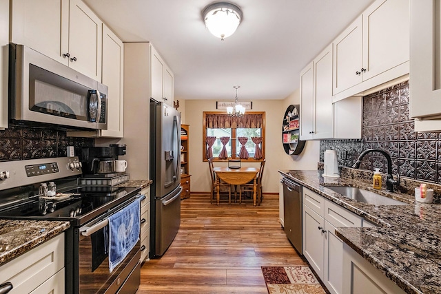 9379 Jamie Dr, Davison, MI 48423 - kitchen with stainless steel appliances, a chandelier, backsplash, light wood-style floors, and white cabinetry