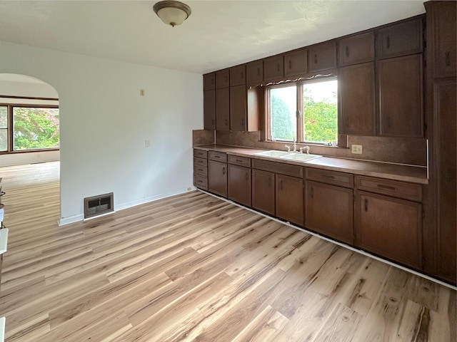 2839 128th Ave, Holland, MI 49424 - kitchen featuring light wood finished floors, tasteful backsplash, arched walkways, and light countertops