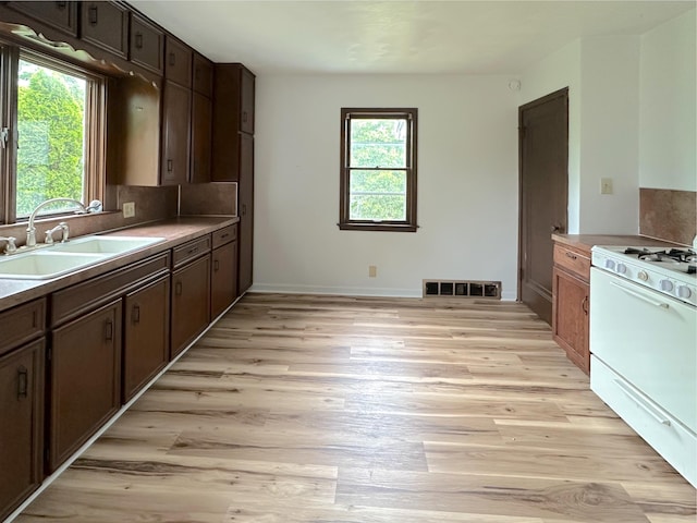 2839 128th Ave, Holland, MI 49424 - kitchen with white gas range, light wood finished floors, backsplash, and dark brown cabinets