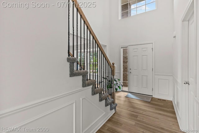 9019 Elbert Dr, Romulus, MI 48174 - foyer featuring a towering ceiling, stairway, wood finished floors, and a wainscoted wall