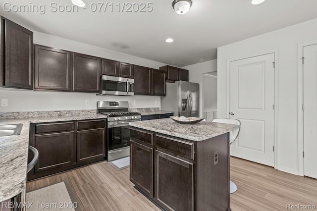 9019 Elbert Dr, Romulus, MI 48174 - kitchen featuring stainless steel appliances, light wood-style floors, dark brown cabinets, a center island, and recessed lighting