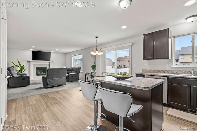 9019 Elbert Dr, Romulus, MI 48174 - kitchen with dark brown cabinets, a center island, a breakfast bar, light countertops, and a chandelier