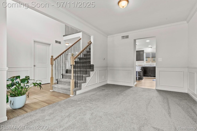 9019 Elbert Dr, Romulus, MI 48174 - unfurnished living room with a decorative wall, carpet flooring, ornamental molding, stairs, and wainscoting