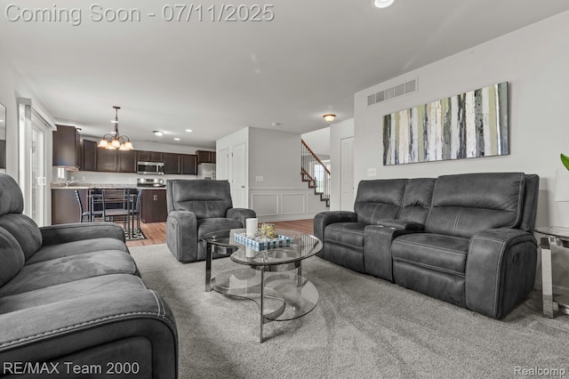 9019 Elbert Dr, Romulus, MI 48174 - living room featuring stairs, a chandelier, recessed lighting, a wainscoted wall, and light wood-type flooring