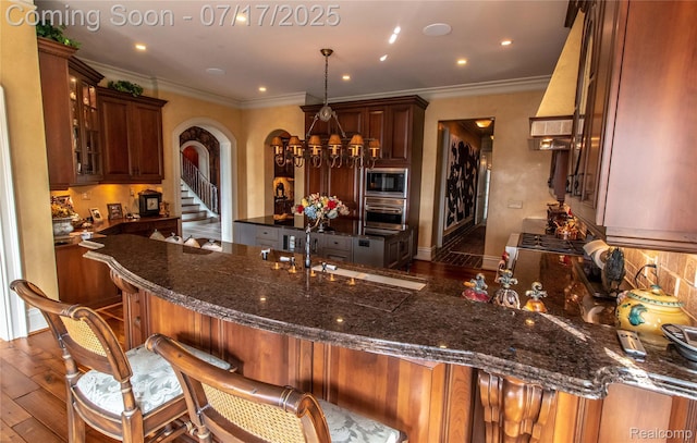 2756 Turtle Bluff Dr, Bloomfield Hills, MI 48302 - kitchen featuring black microwave, arched walkways, dark wood-type flooring, a kitchen breakfast bar, and ornamental molding