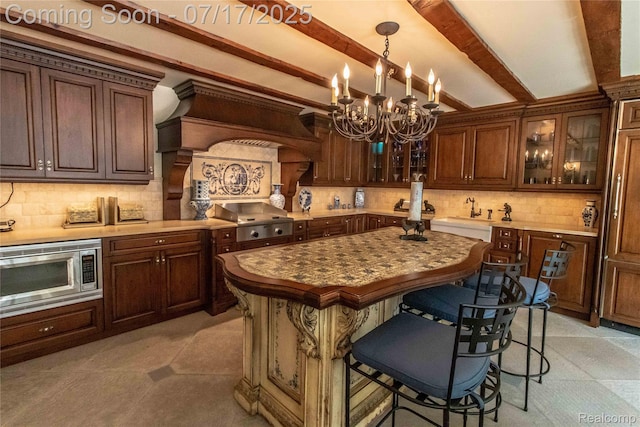 2756 Turtle Bluff Dr, Bloomfield Hills, MI 48302 - kitchen featuring stainless steel microwave, a chandelier, beamed ceiling, backsplash, and premium range hood