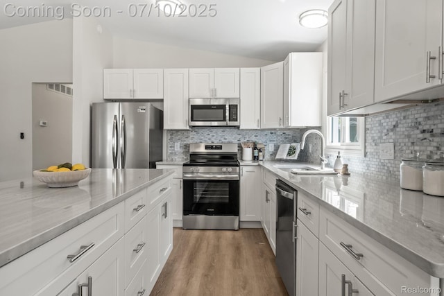 3764 Tyler Ave, Royal Oak, MI 48072 - kitchen featuring appliances with stainless steel finishes, vaulted ceiling, white cabinetry, light stone counters, and decorative backsplash