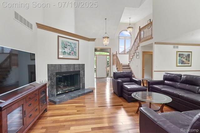 4253 Drexel Dr, Troy, MI 48098 - living room featuring a towering ceiling, stairs, light wood-style flooring, and a tiled fireplace