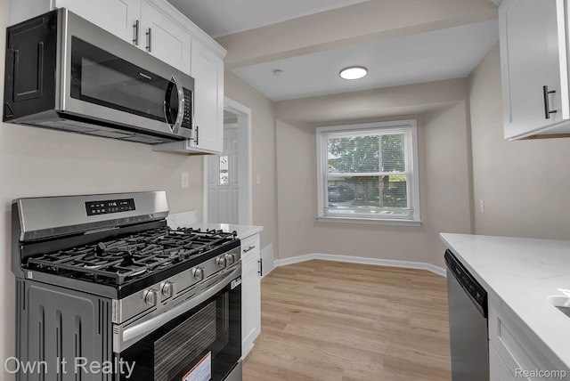 1389 Cleveland Ave, Northville, MI 48146 - kitchen featuring appliances with stainless steel finishes, white cabinetry, light wood-type flooring, and light stone countertops
