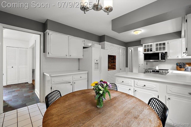 32010 Inglewood St, Franklin, MI 48025 - kitchen featuring white refrigerator with ice dispenser, stainless steel microwave, white cabinetry, a chandelier, and light countertops