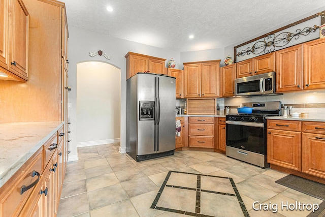 3566 Little Timber Ct SW, Grand Rapids, MI 49534 - kitchen featuring appliances with stainless steel finishes, arched walkways, recessed lighting, tasteful backsplash, and a textured ceiling