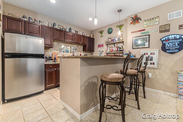 3566 Little Timber Ct SW, Grand Rapids, MI 49534 - kitchen with freestanding refrigerator, a breakfast bar, light tile patterned floors, dark brown cabinetry, and recessed lighting