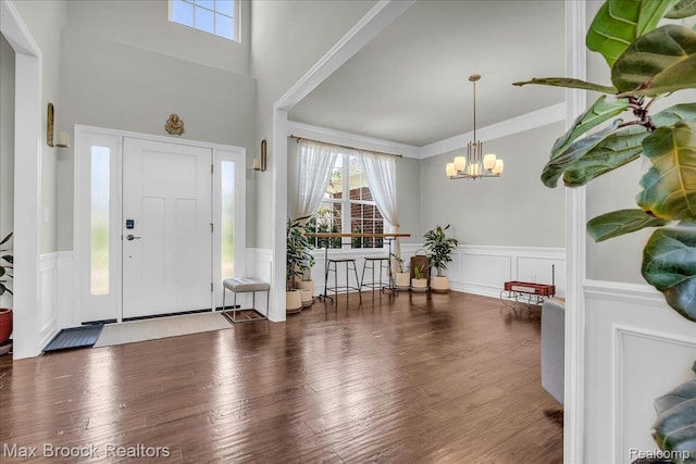 1043 Kendall Ct, Lake Orion, MI 48360 - foyer featuring a chandelier, wainscoting, a decorative wall, wood finished floors, and a towering ceiling