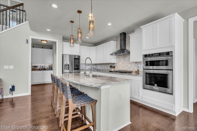1043 Kendall Ct, Lake Orion, MI 48360 - kitchen featuring wall chimney range hood, stainless steel appliances, backsplash, dark wood finished floors, and white cabinetry