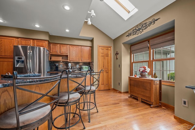 1381 Briarson Dr, Saginaw, MI 48638 - kitchen featuring stainless steel refrigerator with ice dispenser, a skylight, backsplash, brown cabinets, and lofted ceiling