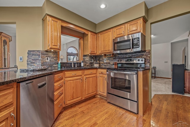 1381 Briarson Dr, Saginaw, MI 48638 - kitchen with appliances with stainless steel finishes, dark stone countertops, light wood-style flooring, and tasteful backsplash