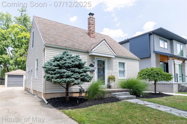 1943 Hazel St, Birmingham, MI 48009 - view of front of house with an outbuilding, a chimney, a detached garage, a front yard, and a shingled roof