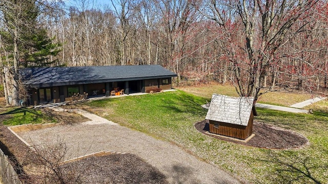 9442 Community Hall Rd, Union Pier, MI 49129 - view of front of house featuring a front yard, a forest view, an outbuilding, and roof with shingles