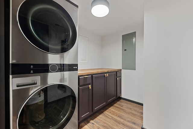 9442 Community Hall Rd, Union Pier, MI 49129 - washroom with stacked washer and clothes dryer, electric panel, cabinet space, and light wood-style floors