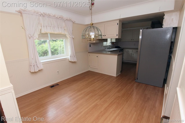 53347 Mark Dr, Shelby Twp, MI 48316 - kitchen featuring freestanding refrigerator, light wood-style flooring, wainscoting, decorative light fixtures, and a peninsula