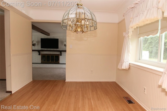 53347 Mark Dr, Shelby Twp, MI 48316 - unfurnished dining area featuring a wainscoted wall, wood finished floors, a chandelier, and a brick fireplace