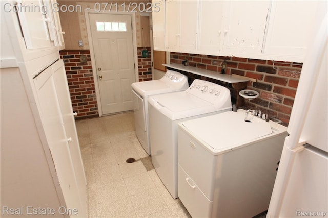 53347 Mark Dr, Shelby Twp, MI 48316 - laundry room with washing machine and clothes dryer, light flooring, brick wall, and cabinet space