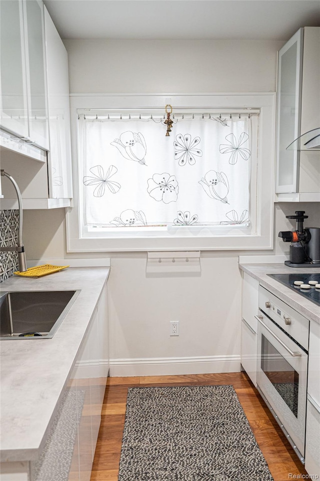 1036 Irving Ave, Royal Oak, MI 48067 - kitchen featuring oven, black electric stovetop, light wood-type flooring, and light countertops