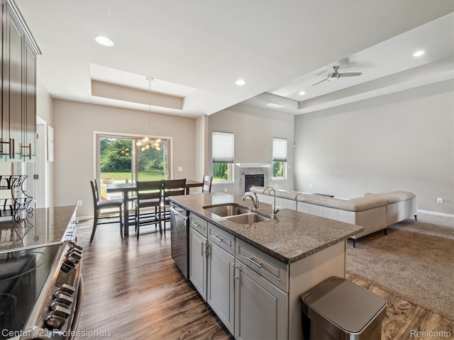 2655 Devondale Rd, Rochester Hills, MI 48309 - kitchen with a tray ceiling, stainless steel appliances, open floor plan, a lit fireplace, and gray cabinets