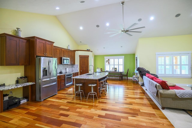 9434 84th St SE, Alto, MI 49302 - kitchen featuring appliances with stainless steel finishes, open floor plan, light wood-type flooring, a kitchen breakfast bar, and ceiling fan