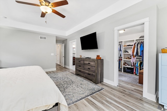 711 N Alexander Ave, Royal Oak, MI 48067 - bedroom with light wood-style flooring, a walk in closet, a closet, a ceiling fan, and a raised ceiling