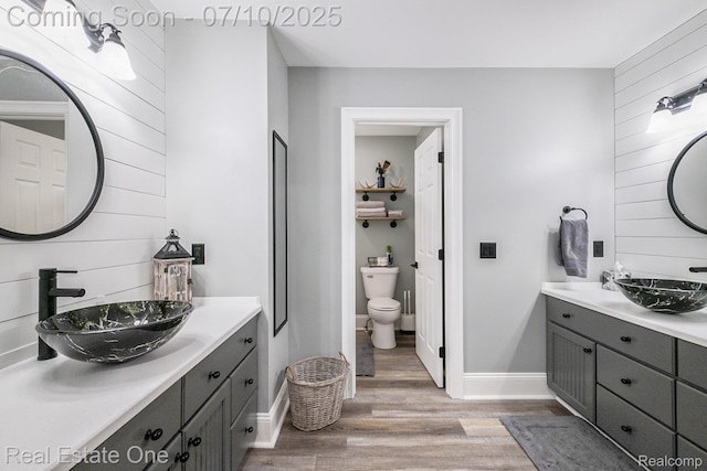 359 High Bluffs Dr, Ortonville, MI 48462 - bathroom featuring wood finished floors, two vanities, and wooden walls