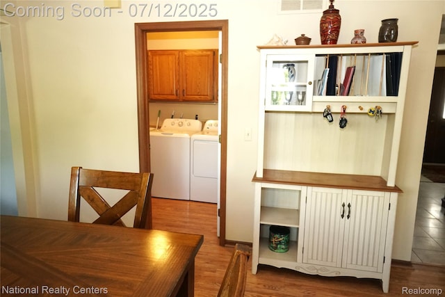 19230 Augusta Ct, Livonia, MI 48152 - washroom with washing machine and dryer, cabinet space, and wood finished floors