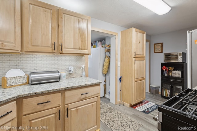204 W Caroline St, Bellevue, MI 49021 - kitchen with light brown cabinetry, decorative backsplash, freestanding refrigerator, light wood finished floors, and light stone countertops