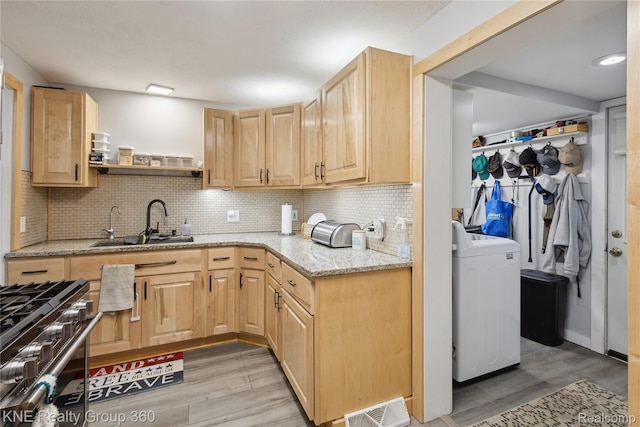 204 W Caroline St, Bellevue, MI 49021 - kitchen with washer / dryer, gas range, light brown cabinets, and light wood finished floors