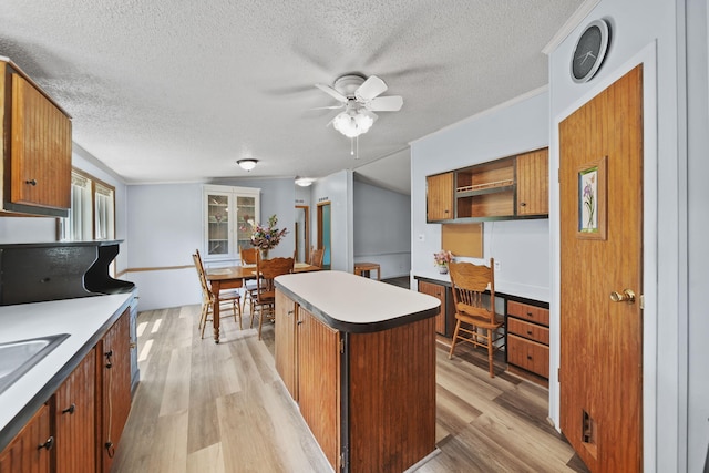 8756 Portage Lake Rd, Munith, MI 49259 - kitchen featuring ceiling fan, light wood-type flooring, a textured ceiling, brown cabinets, and a kitchen island
