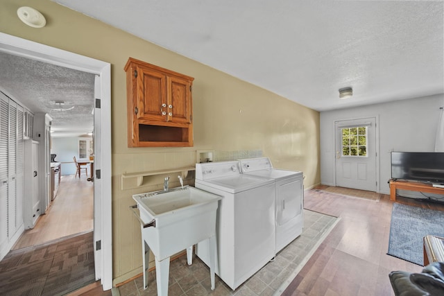 8756 Portage Lake Rd, Munith, MI 49259 - washroom with a textured ceiling, washing machine and dryer, cabinet space, and light wood-type flooring