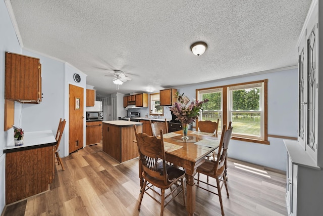8756 Portage Lake Rd, Munith, MI 49259 - dining area with light wood-style flooring, ceiling fan, a textured ceiling, and ornamental molding