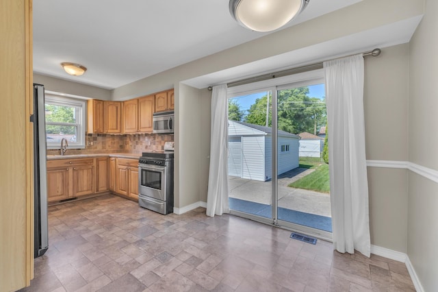 9623 Fairfield St, Livonia, MI 48150 - kitchen featuring appliances with stainless steel finishes, stone tile flooring, backsplash, and light countertops