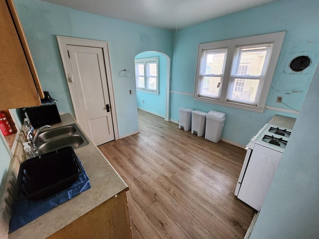 1110 Watkins St SE, Grand Rapids, MI 49507 - kitchen with white gas range oven, arched walkways, light wood finished floors, light countertops, and a desk