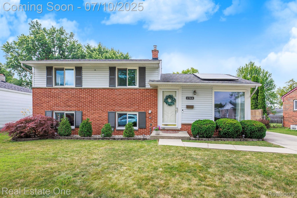 2344 Winston, Sterling Heights, MI 48310 - tri-level home with brick siding, a chimney, roof mounted solar panels, and a front lawn